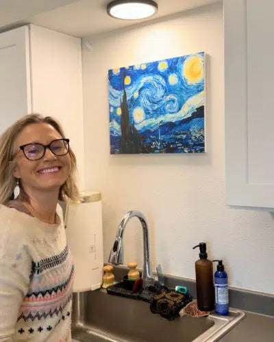 Woman in a kitchen with a 'Starry Night' painting on the wall