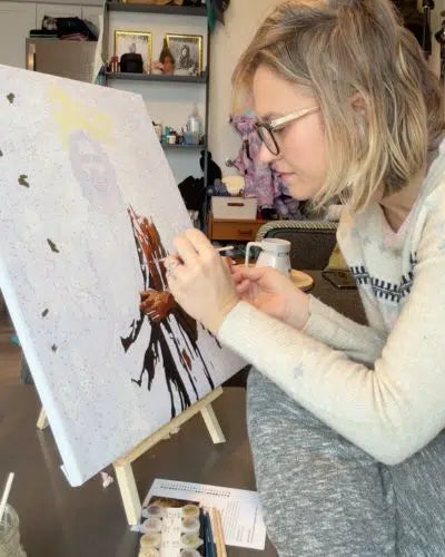 Person painting on a canvas with a focus on the art and artist.