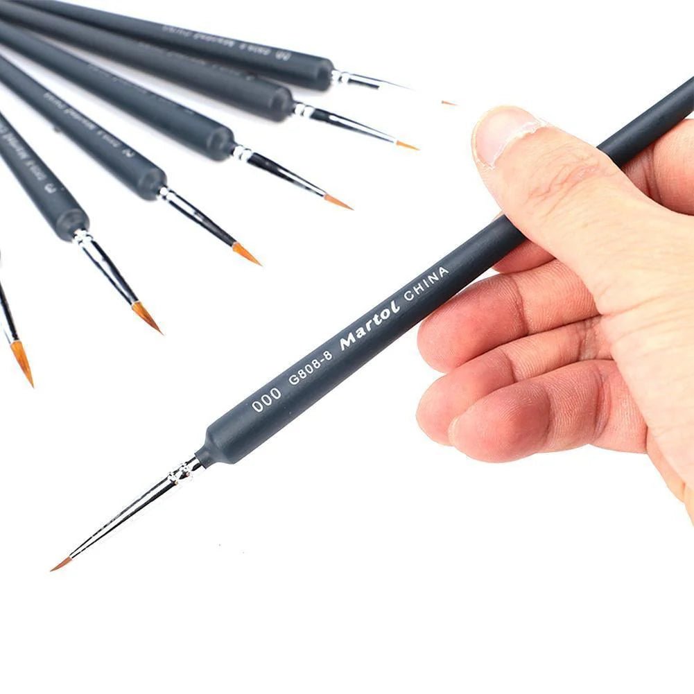 Set of small paintbrushes with a hand holding one, on a white background