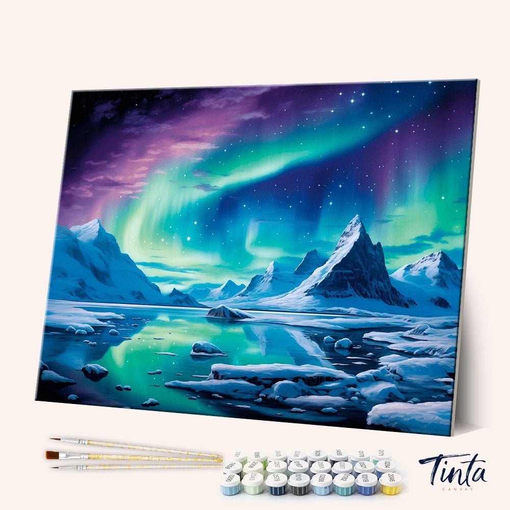 Angled display of the Arctic Glow paint by numbers kit showing northern lights canvas with brushes and paint pots by Tinta Canvas