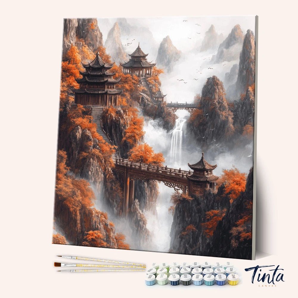 Angled display of the Autumn Mountain Sanctuary paint by numbers kit showing misty temple mountainscape canvas with brushes by Tinta Canvas