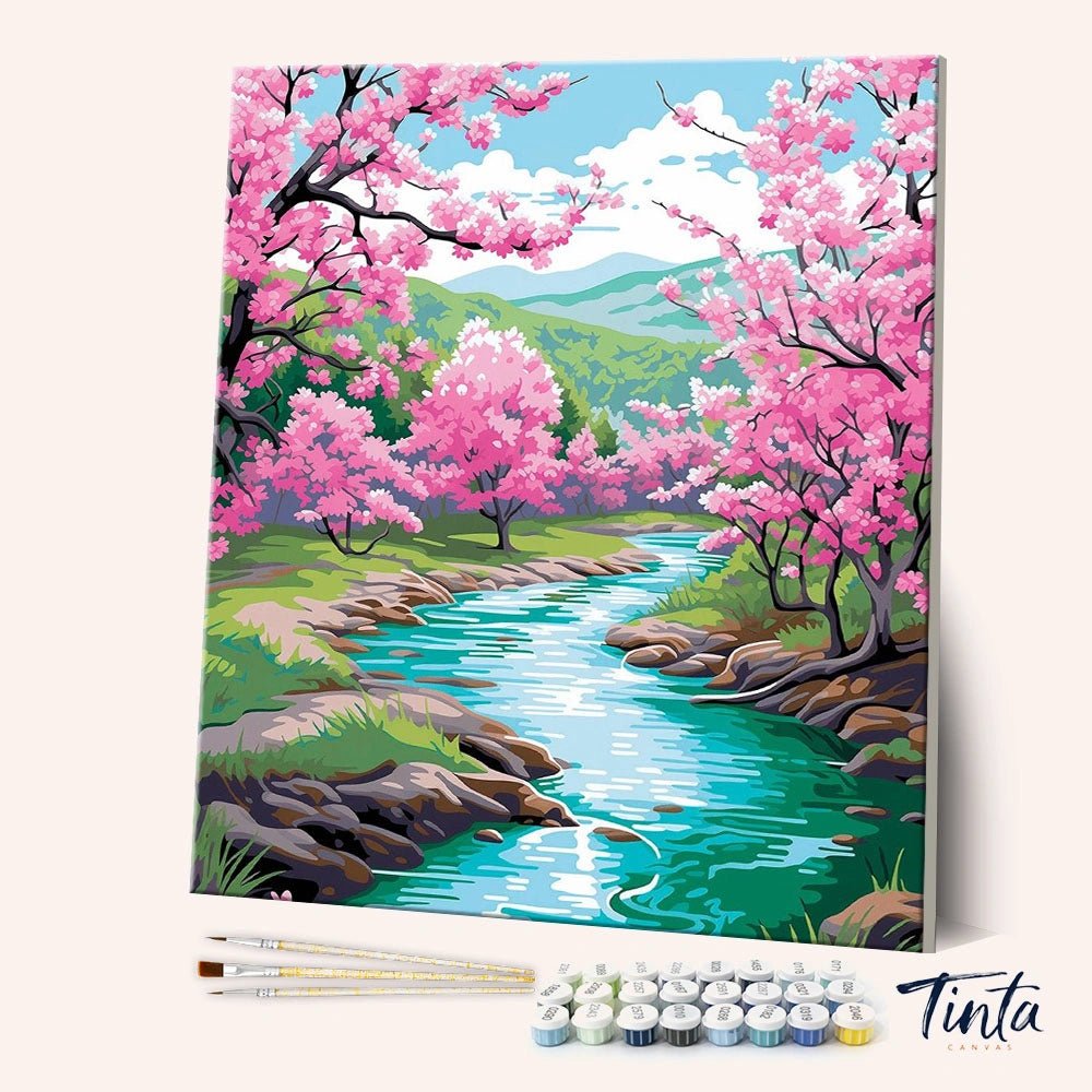 Blossom River Trail paint by numbers kit angled view showing flowing river with pink blossom trees and rocks