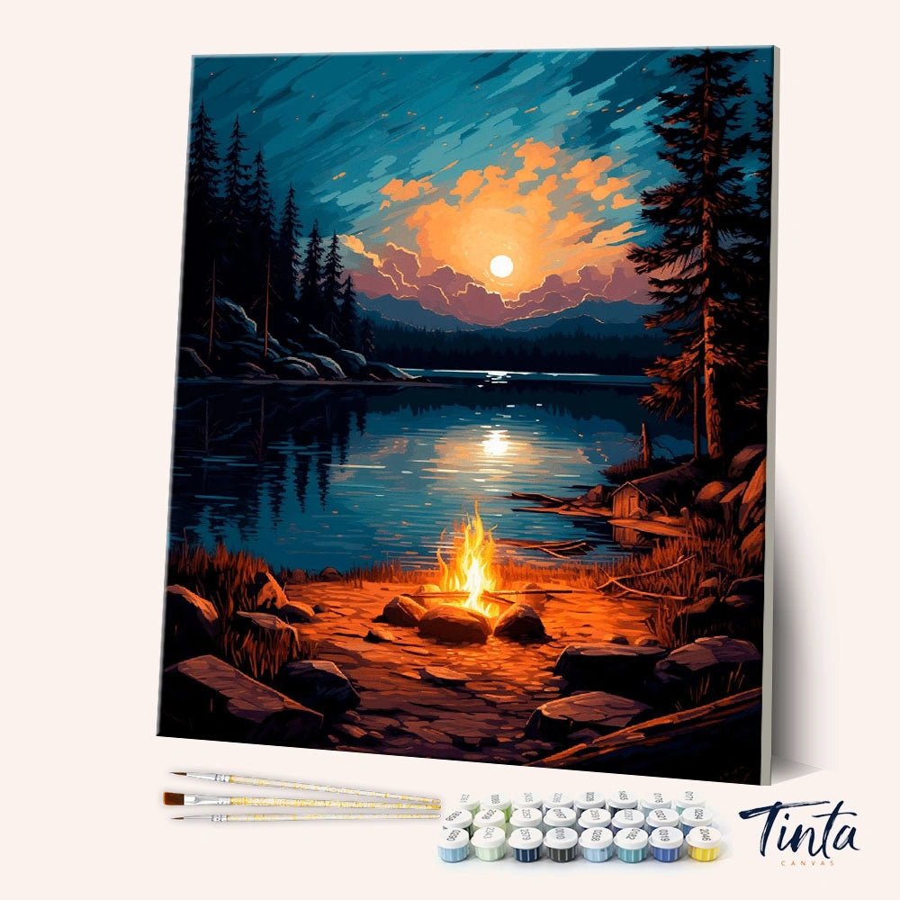 Angled display of the Campfire Reflections paint by numbers kit showing a glowing campfire beside a calm mountain lake by Tinta Canvas