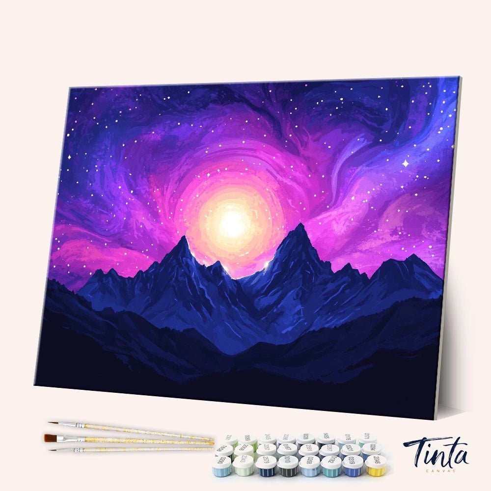 Angled display of the Celestial Awakening paint by numbers kit featuring glowing cosmic light above mountain peaks by Tinta Canvas