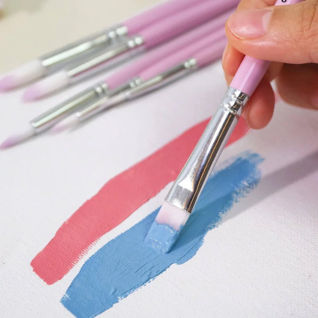 Set of paintbrushes with pink handles on a white surface with paint strokes.
