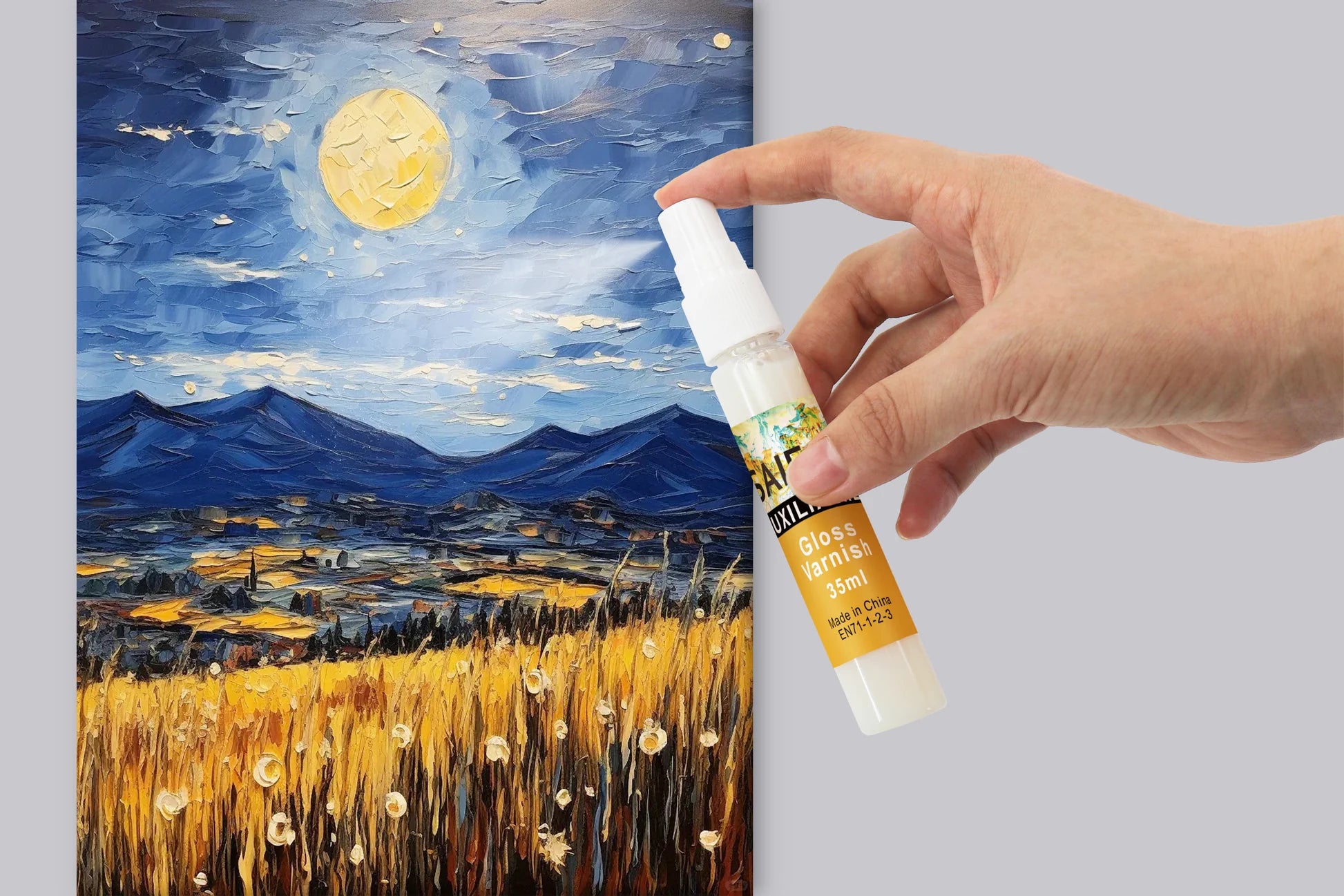 Hand holding a bottle of glass cleaner next to a painting of a night scene with mountains and fields.