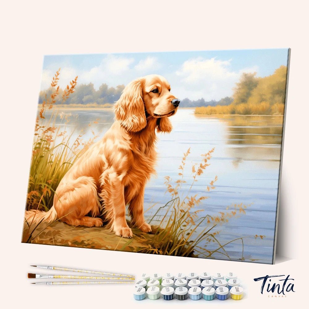 Angled display of Lakeside Golden paint by numbers kit showing a golden retriever sitting beside a calm lakeside landscape by Tinta Canvas