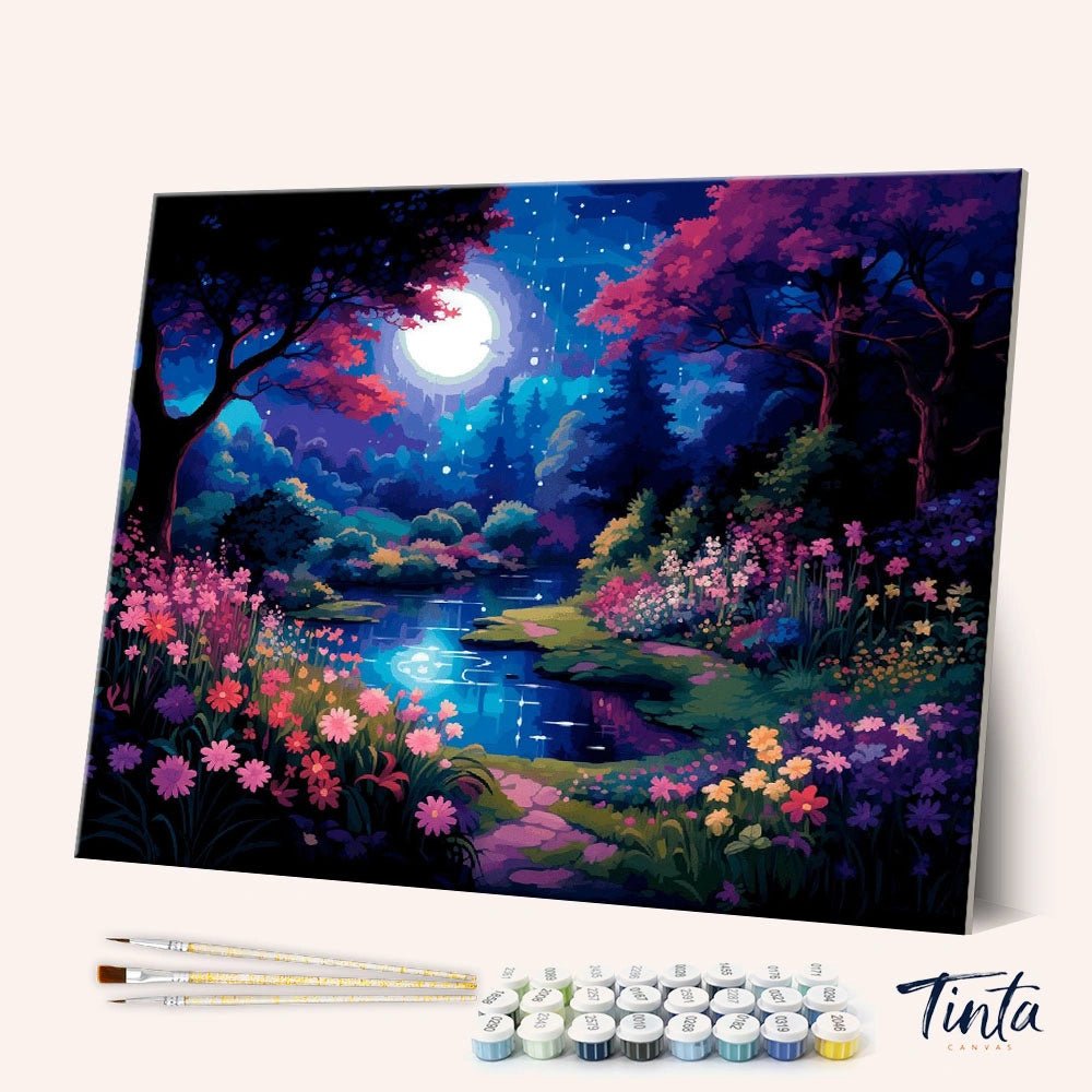 Angled display of the Moonlit Garden Stream paint by numbers kit showing moonlit garden canvas with brushes and paint pots by Tinta Canvas
