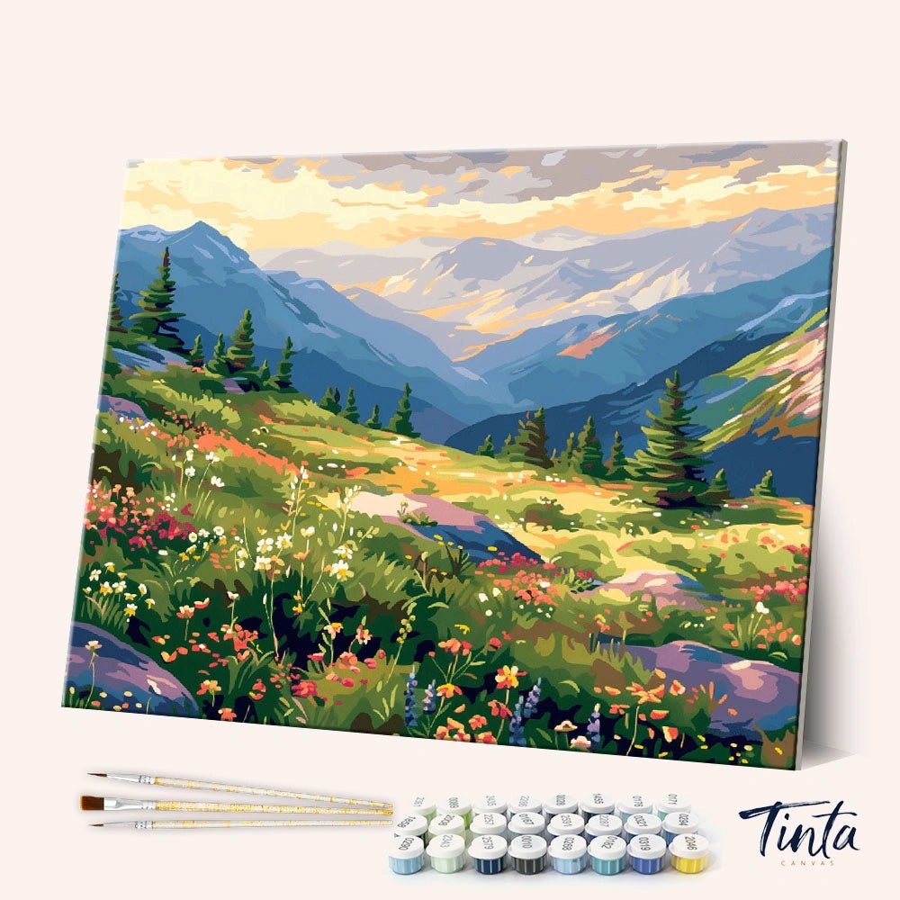 Angled display of the Mountain Wildflowers paint by numbers kit showing colorful alpine meadow canvas with brushes and paint pots by Tinta Canvas