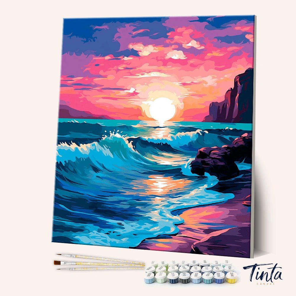 Angled view of Ocean Sunset Glow paint by numbers kit showing vivid sunset over ocean waves with brushes and paints included by Tinta Canvas