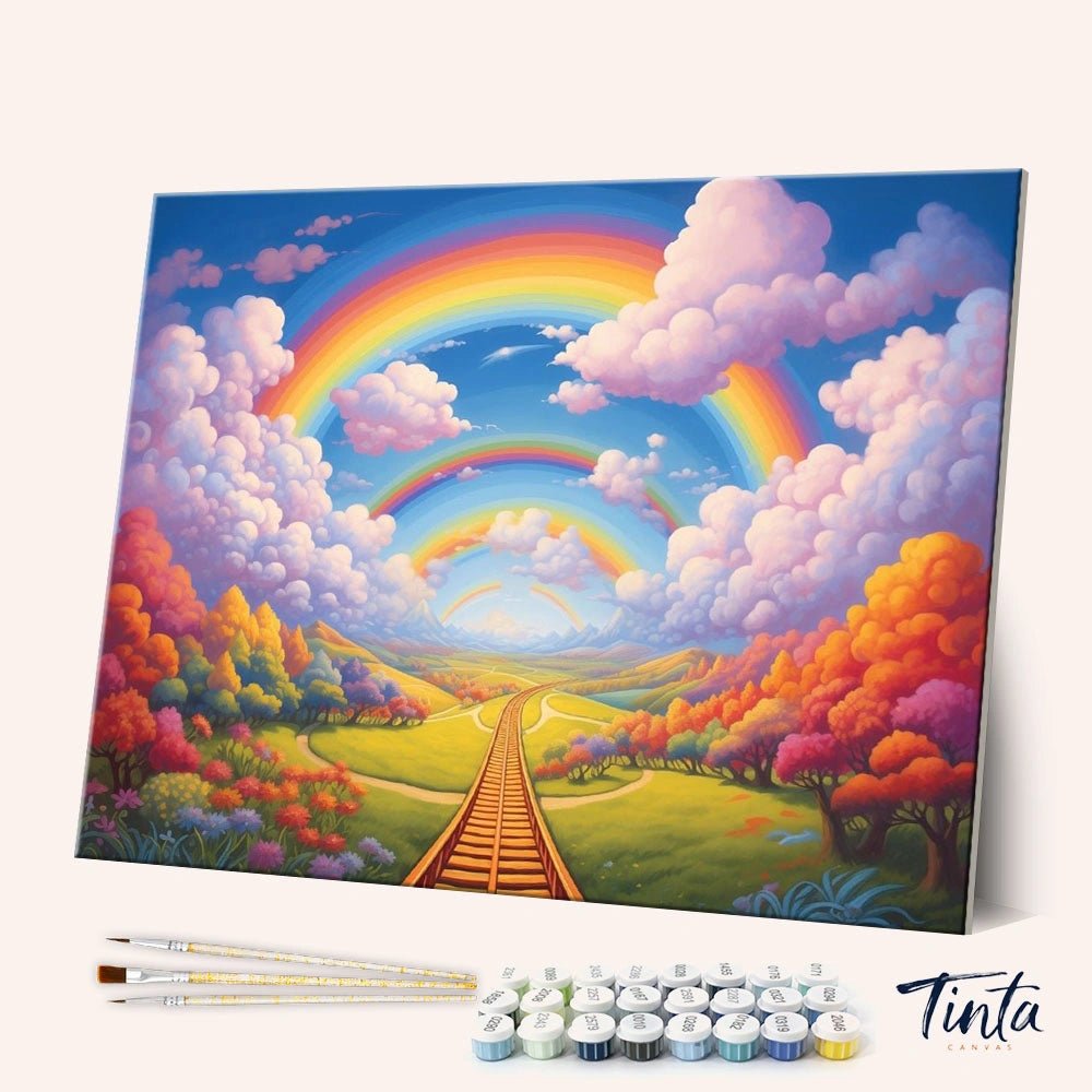 Angled display of the Rainbow Journey paint by numbers kit showing colorful rainbows over a dreamy landscape path by Tinta Canvas