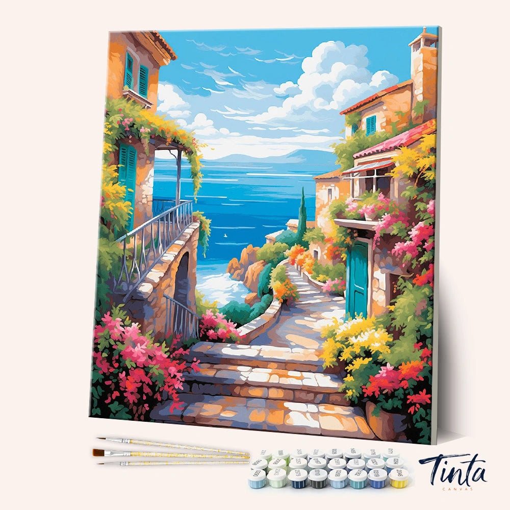 Angled view of Seaside Blossom Path paint by numbers kit featuring colorful coastal homes and ocean view by Tinta Canvas
