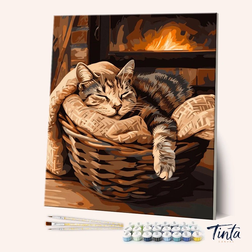 Sleeping Cat paint by numbers kit angled view showing cozy cat resting in basket by warm fireplace