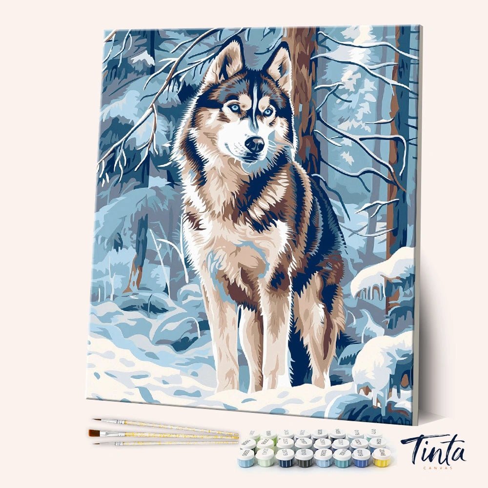 Angled view of Winter Sentinel Wolf paint by numbers kit featuring blue eyed wolf in snowy forest by Tinta Canvas
