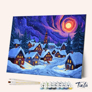 Winter Village paint by numbers kit angled view showing cozy snow-covered houses under glowing colorful night sky