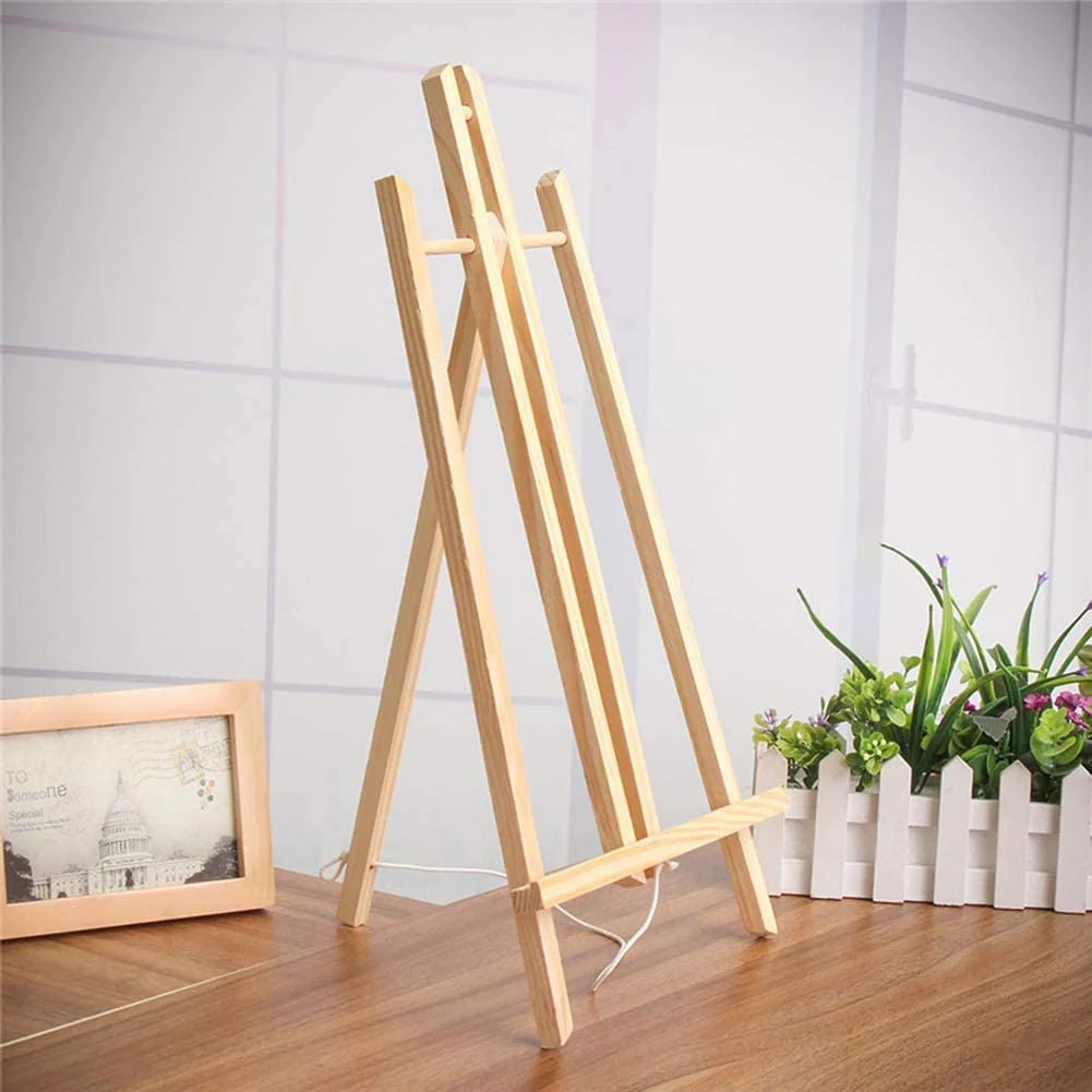 Wooden easel on a wooden floor with a white wall and plants in the background